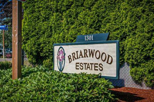 A sign that says brairwood estates in front of bushes.